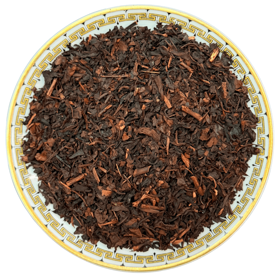 Dry black tea leaves on a decorative plate with a white background