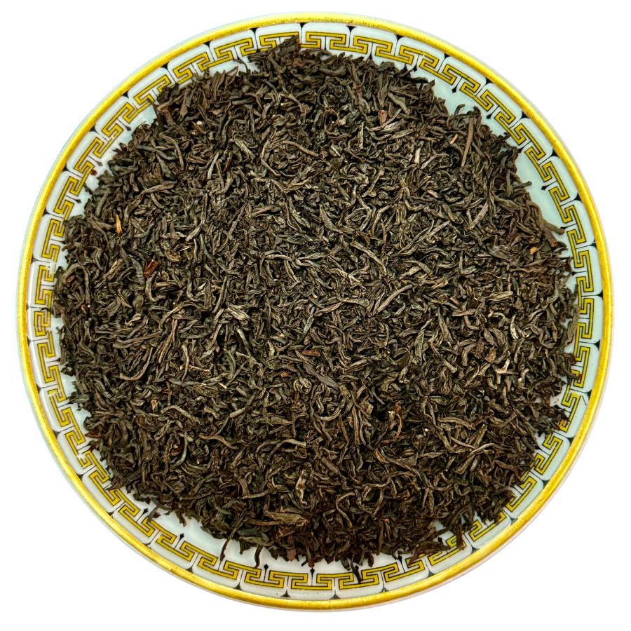 Black Tea leaves on a decorative ceramic plate with a yellow rim