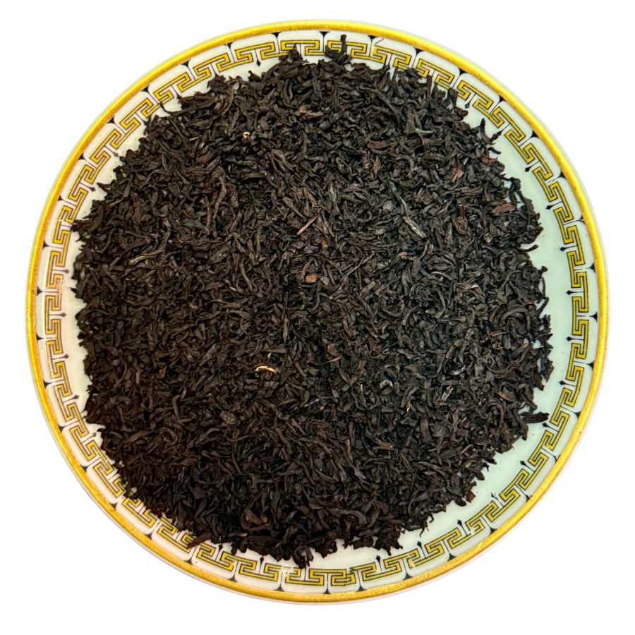 Black tea leaves on a decorative ceramic plate with a yellow rim