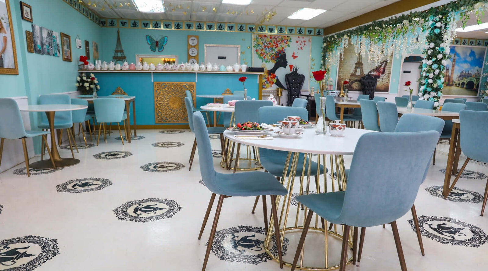 Dining area with blue chairs and tables against a decorated wall.