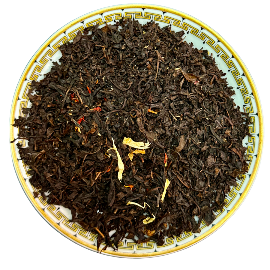 Dry black tea leaves on a decorative plate with a white background
