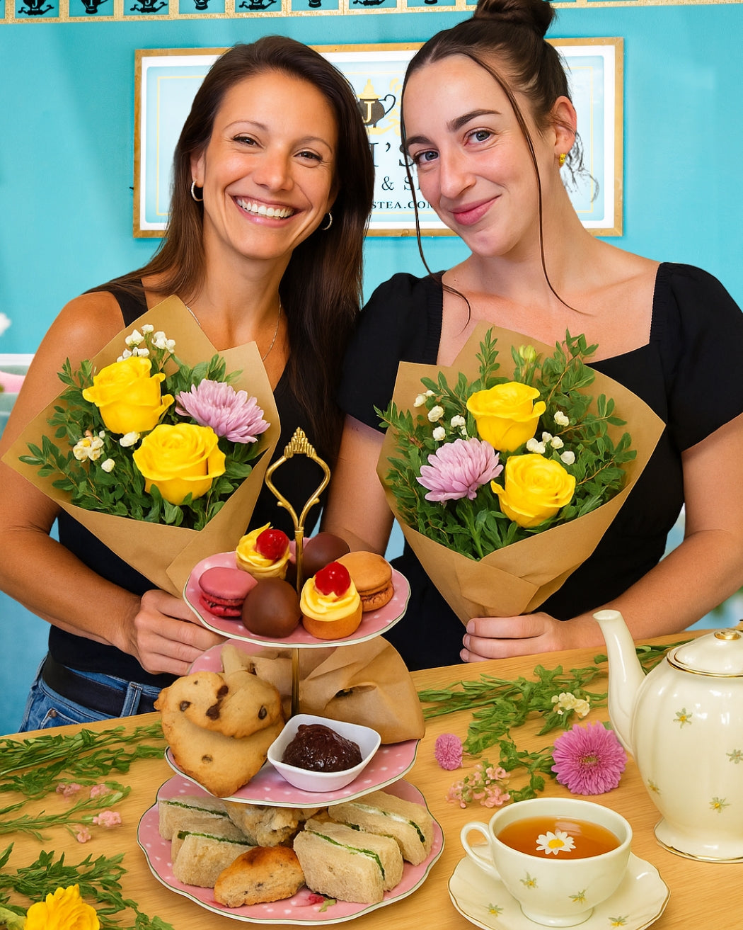Two women holding flower bouquets and a plate of pastries in a classroom setting.