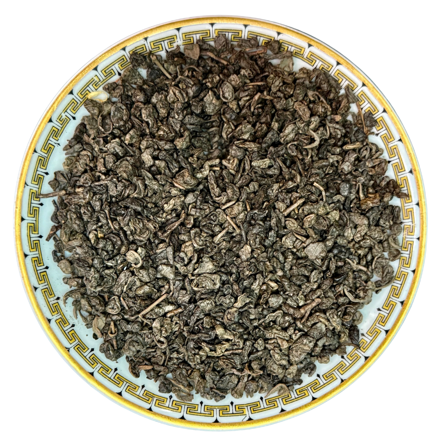 Dry tea leaves on a decorative ceramic plate with a white background