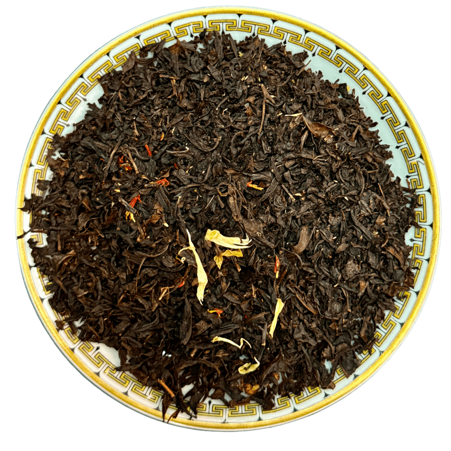 Dry black tea leaves on a decorative plate with a white background