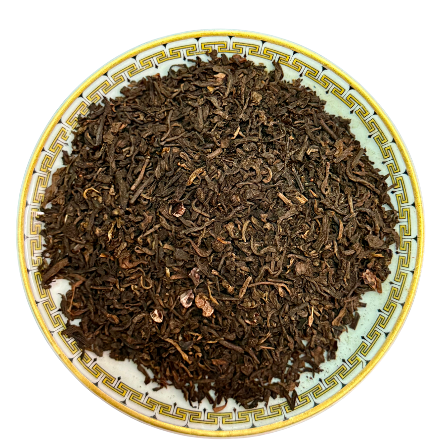 Dry tea leaves on a decorative ceramic plate with a white background