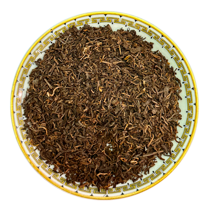 Dried tea leaves on a decorative ceramic plate with a white background
