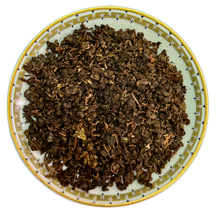 Dry tea leaves on a decorative ceramic plate with a white background