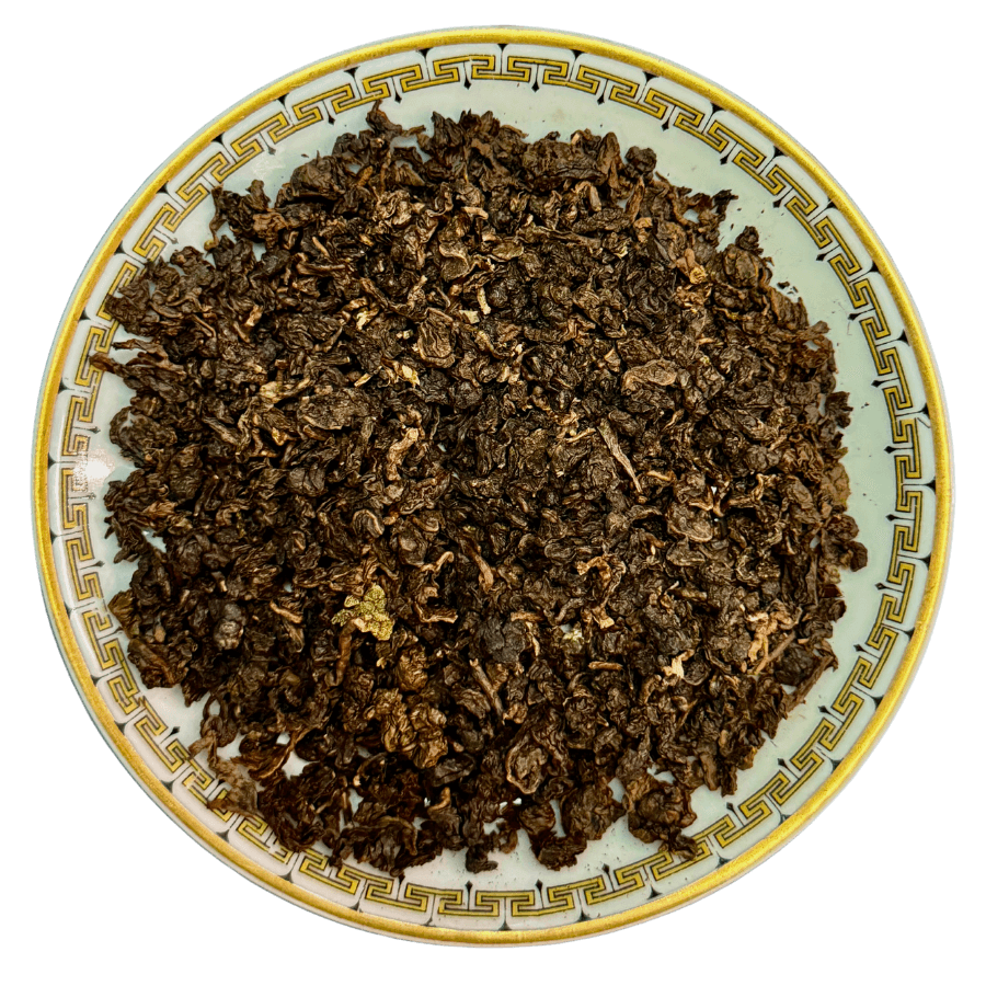 Dry tea leaves on a decorative ceramic plate with a white background